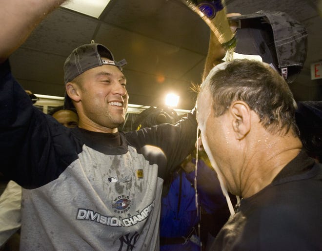 Derek Jeter gives manager Joe Torre a champagne shower as the team celebrates after clinching its ninth consecutive American League East title last night in Toronto. The Yanks actually lost the game, but clinched after the Twins knocked off the Red Sox.