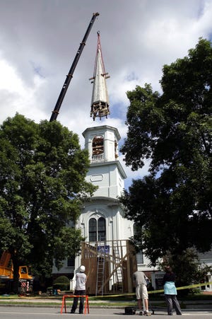 A crane lifts the 45-foot-tall steeple from the top of the First Universalist Church Aug. 30, 2006, in Yarmouth, Maine. The 146-year-old steeple is being stored on the church's front lawn until $330,000 is raised to restore it, along with the deteriorated wooden belfry and tower that support it. Churches across New England are facing similar problems with their aging wooden steeples. (AP Photo/Robert F. Bukaty)