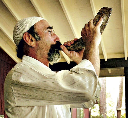 Dennis Shuman demonstrates blowing the shofar that he made at his northwest Gainesville home Friday.