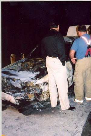 Police and fire investigators look over the scene of a car fire Thursday that killed a man.
