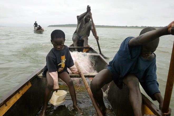On Lake Volta in Ghana, Mark Kwadwo, 6, left, scoops water in the canoe of Kwadwo Takyi, rear. Kwabena Botwe, 11, paddles.