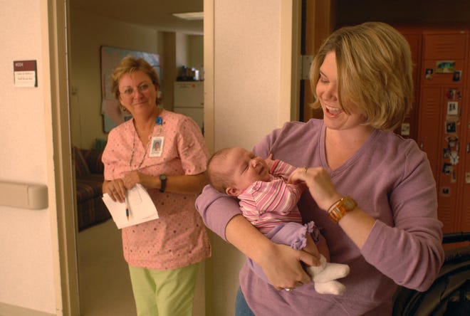 Rebecca Reece holds her four-week-old daughter, Madeline Elizabeth, as head nurse Cindy Ochoa looks on in the labor and delivery ward at Winn Army Community Hospital.