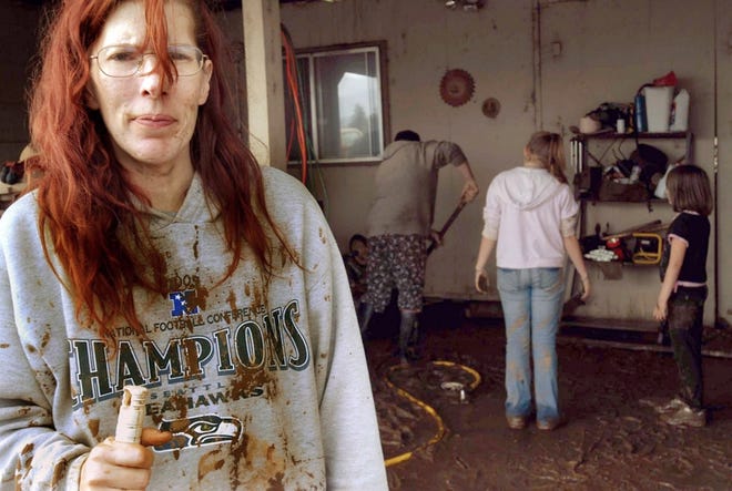 Sonja Hollingsworth, left, is covered with mud while attempting to clean her home in Tillamook, Ore., Wednesday. The Hollingsworths spent two nights in a hotel to escape flood waters from heavy rain.
