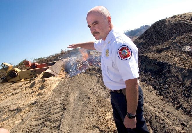 Marion County Fire-Rescue Fire Marshal and Division Chief Paul Nevels inpects a controlled burn of trees and debris at the Meadow Glen development on Southwest 99th Street Road on Thursday. A device known as an air curtain incinerator, at left, is being used to control the fire.