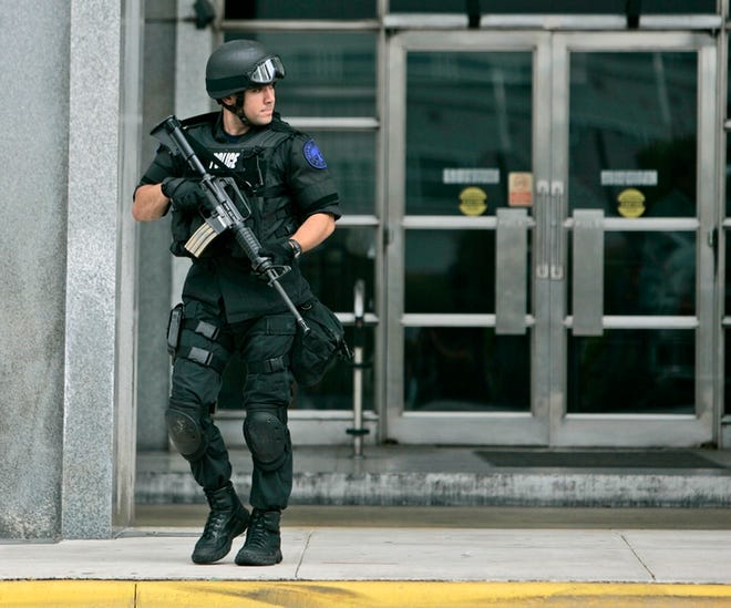 A SWAT team member leaves the Herald offices.