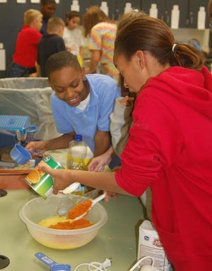 Levaun Green watches Erica Harris pour a can of pumpkin mix into a bowl during class at Warren Road Elementary School.