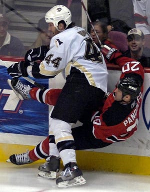 Pittsburgh's Brooks Orpik (left) dishes out a hard check to New Jersey's Jay Pandolfo in Friday's game in New Jersey.