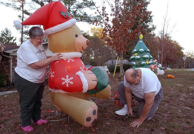 Malene Bright holds the Christmas bear straight as her husband, Donald Bright, secures it to the ground. They are getting their home ready for Christmas and their 11 grandchildren.