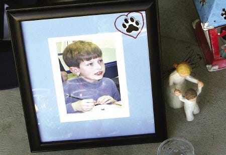 A framed photograph of Thomas Fogarty, 9, is placed with candles as part of a memorial outside the Fogarty residence in Greenland on Monday.