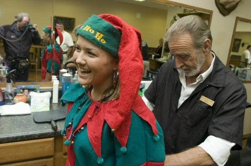 Heather Coven gets some help with her Elf outfit from fellow stylist Dan McIntyer as stylists in Cal's Barbarshop prepare for their appearance in the upcoming Christmas parade in the The Villages.
