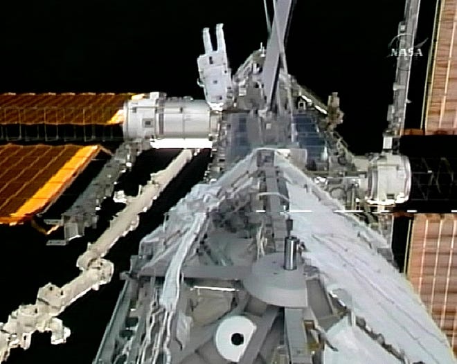 Space walker Christer Fuglesang, top center, works to install a 2-ton addition to the space station Tuesday in this image from NASA television.