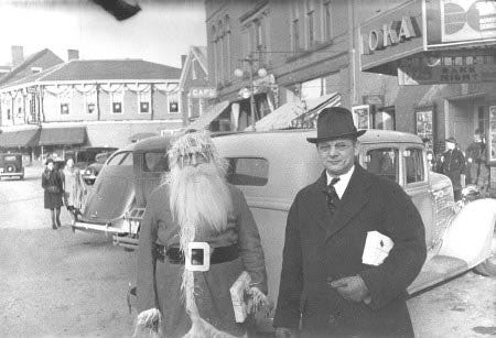 Christmas in downtown Exeter, 1938. Santa (Walter Pennell) and local restaurateur, Paul Bretschneider, stand outside the Ioka theater for the annual Lions Club children?s party.
			Photo courtesy of the Exeter Historical Society