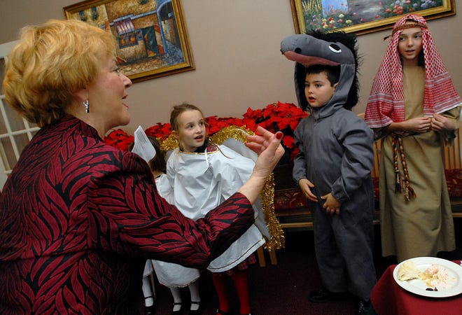 Nikki Stournaras, left, directs Mikaela Gjoka, dressed as an angel, Michael Stournaras, dressed as a donkey, and Eleni Kovatsis, dressed as a shepherd, in some caroling for customers at Nicholas Restaurant in Natick yesterday.