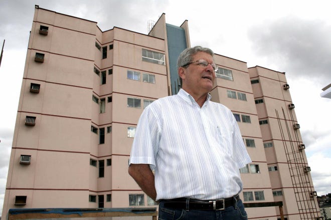 Luiz Alberto Jardim stands in front of a building in Valadares, Brazil, built with money from America.