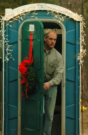 Mark Dailey of Garren Construction is surprised by a photographer as he exits a Port-O-let decorated with lights and a wreath at a construction site on Reid Place in Augusta. Carl Menger, the owner of a nearby home said that if they didn't move the toilet, that he would decorate it. The small sign on the door reads "Santa's Pitstop.