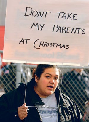 Mónica Salazar, de 26 años, sostiene una pancarta que lee "No se lleven a mis padres en Navidad", luego de una redada de inmigración en Colorado.