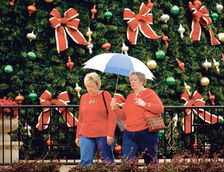Two women share an umbrella as they pass a Christmas Tree display at Lakeside Village in Lakeland on Tuesday.