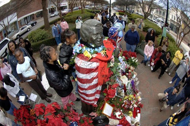 Fans gather Friday at the adorned James Brown statue on Broad Street in Augusta to pay tribute to the Godfather of Soul. Mr. Brown's funeral is at 1 p.m. today, after a public viewing.