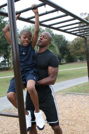 Adrian Clinton assists his 10-year-old son, Christian, on the monkey bars at Jervy Gantt Park.