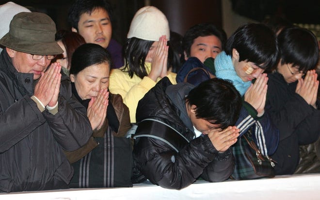Japanese worshipers pray for the luck of the New Year near Tokyo's Zojoji Temple during their first visit of the year early today Japan time. Other Japanese climbed Mount Fuji to mark the New Year.