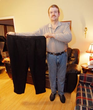 Jimmy Dorsett, 41, who has lost nearly 130 pounds since starting the YMCA's Shrinkdown program in 2006, holds up some pants that fit him a year ago.