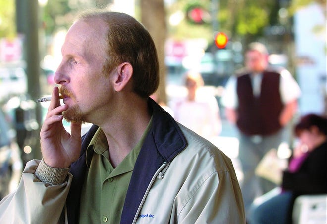 Carl Vickery, who works downtown, smokes a cigarette Tuesday on North Front Street in Wilmington. The city has plans to install ashtrays in the area as part of a plan to clean up city streets and sidewalks.
