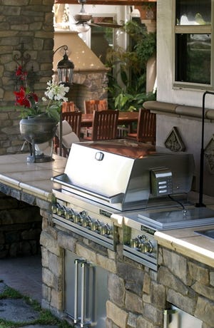 A large stainless grill and accessories are set in the stone ans tile counter in the patio of Nick Marzilliano's home in Clovis, Calif.