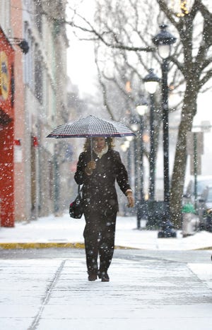 WINTER IN THE AIR: Denise Tasick of East Stroudsburg makes her way down Main Street in downtown Stroudsburg during a brief snow shower late Monday afternoon.