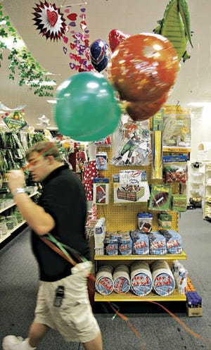 Brandon Gilliland, assistant manager of the Simply Unforgettable Party shop, walks past the store's Super Bowl XLI party supply display.