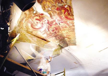 Bryon Roesselet of Evergreene Painting Studios uncovers 19th century artwork as he works to restore the dome inside The Music Hall on Thursday. The theater is undergoing a major restoration, which officials say will be completed by September.