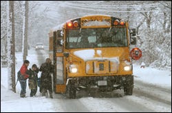 Children get into a school bus with the help of an adult yesterday morning on Ocean Street in Hyannis as snow falls. Some bus drivers on Cape Cod complained that school starting times should have been delayed to allow plows time to clear the roads.
