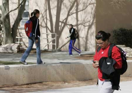 Three pedestrians using cell phones pass near the student union building on the University of New Mexico campus in Albuquerque, N.M. Peter Leyden, director of the New Politics Institute, which has been studying the potential impacts of cell phones on political and social campaigns, says that about 4 in 5 voting-age Americans have cell phones, and that number is expected to keep growing.

			AP photo