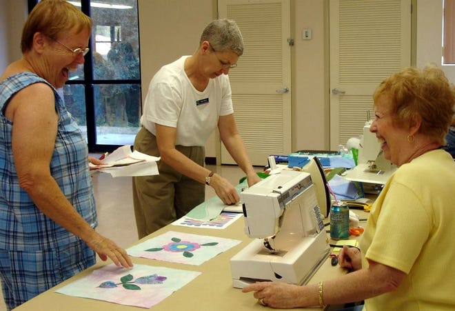 Jan Nascimbeni, left, and Barb Haines share a laugh during the National Quilt Day celebration. Haines was demonstrating hand quilting by machine techniques.