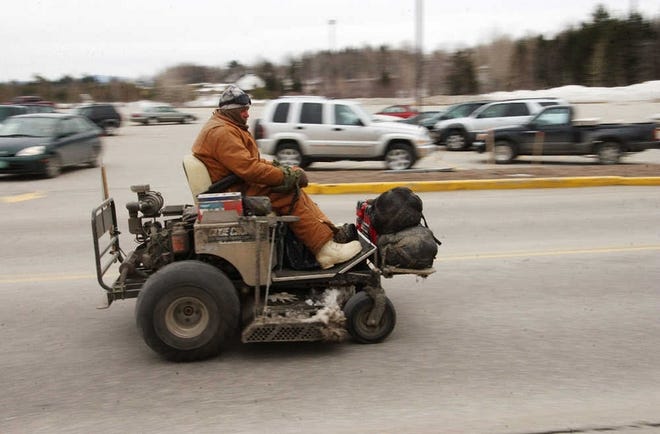 Louis Ransom, also known as “Travlndude,” of Fife Lake, Mich., who is trying to drive around the country on a lawnmower to raise money for charity, drives his lawnmower though the Berlin Mall parking lot Friday morning in Berlin, Vt.