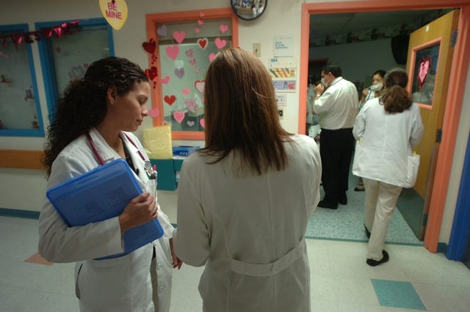 Dr. Solimar Afanador, left, checks some paperwork with another doctor at All Children's Hospital in St. Petersburg. Most medical students in Florida leave the state to do their residencies.