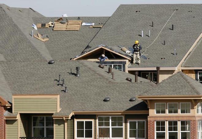 Workers toil on the roof of a new condominium complex being built in east Denver. Construction of new homes rebounded in February after a big decline in the previous month, but building permits slid further, indicating future problems.