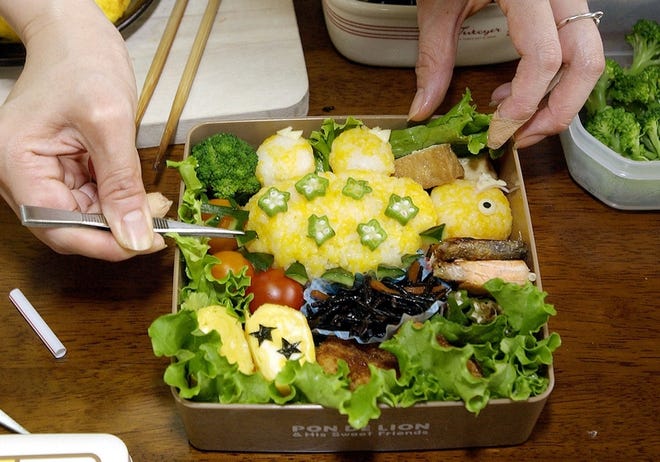 Kazumi Shimomura puts final touches on a box lunch for her son in Ichihara, Japan, on June 21. She sculpted white rice into the shape of a dinosaur, fashioned its eyes with slices of cheese.