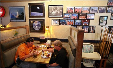 Brian and Becky Bosarge dine at Shuttles Bar and Grill, a classic roadhouse in Merritt Island, Fla. The restaurant’s interior is decorated with photographs of astronauts and other NASA images, while the exterior entices visitors with an eight-foot portrait of the shuttle in flight.
