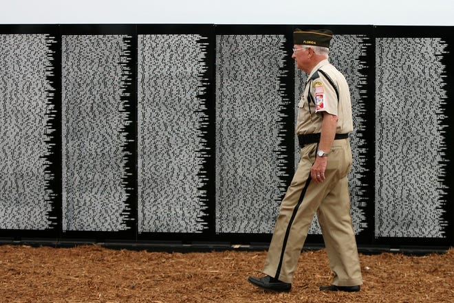 Veterans of Foreign Wars Post No. 4252 Honor Guard member Bud Riffe walks past a section of the Vietnam Traveling Memorial Wall on Thursday at On Top of the World on State Road 200 in Ocala.