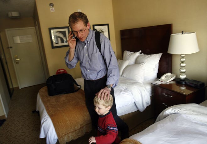 John Stultz, top, talks on the phone to his wife alongside his son, Luke, after arriving at the Marriott Hotel in Raleigh, North Carolina, March 14 2007. Stultz, an engineer and manager for SAS, and others are squeezing time in with kids any way they can, which means business trips with children in tow. (Jason Arthurs/Raleigh News & Observer/MCT)