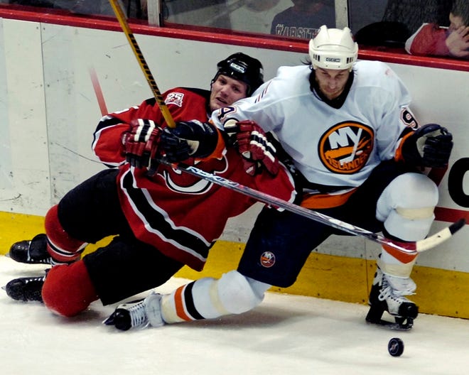 The Islanders' Ryan Smyth, right, holds off the Devils' Colin White. The Isles clinched a playoff spot Sunday.