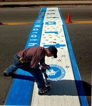 Jacques LeDuc paints the Boston Marathon starting line in downtown Hopkinton this afternoon.