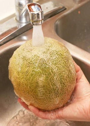 Running melons under water cleans crevices of dirt that could contaminate the cut fruit.