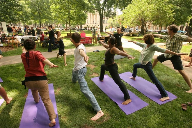 Jennifer Wofsey, background at left, leads an impromptu yoga session during Sunday’s Earth Day on the Quad.
