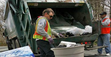 Department of Public Works workers Danny Miller, right, and Steven Pelletier collect trash in Dartmouth, where a budget deficit has led the Select Board to propose a “pay-as-you-throw” program, which attaches a $2 fee for each bag of garbage.