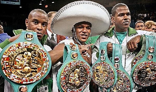 Floyd Mayweather, center, capped off his victory over Oscar De La Hoya on Saturday night – for De La Hoya’s 154-pound title – by showing off his championship belts, with a little help from his handlers.
