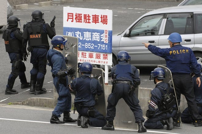Japanese police officers take up their position by a parking lot near a house where an armed man went on a shooting spree at Nagakute, central Japan, on Friday.