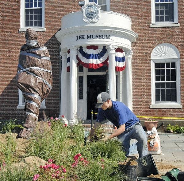 Greg Wall of KMK Landscape Design and Installation of Centerville plants beach grass around the base of the new John F. Kennedy statue at the John F. Kennedy Hyannis Museum yesterday.
