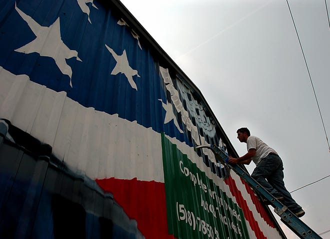 Painter Victor Chaves of Framingham works on a patriotic mural for Camuso Automotive on 100 Main Street in Milford Friday afternoon. Chaves and partner Steve Logan have been working on the mural  for two weeks and expect to finish early next week.
