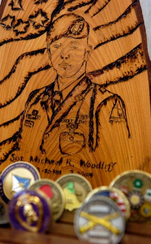 Commander's coins earned by Michael Woodliff sit in front of a carving of his likeness and a photograph of him in his father's office in Punta Gorda. A customer made the engraving as a gift.